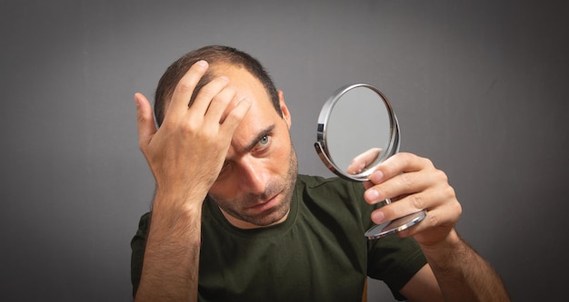 Uomo che guarda allo specchio Concetto di perdita di capelli