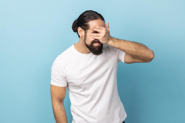 Uomo che guarda attraverso le dita che sbirciano con una faccia curiosa che ha segreti di osservazione sospetti