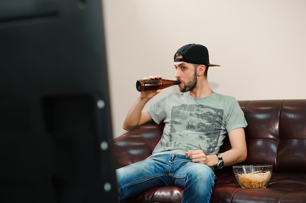 Uomo che guarda il calcio e bere birra, tifoso