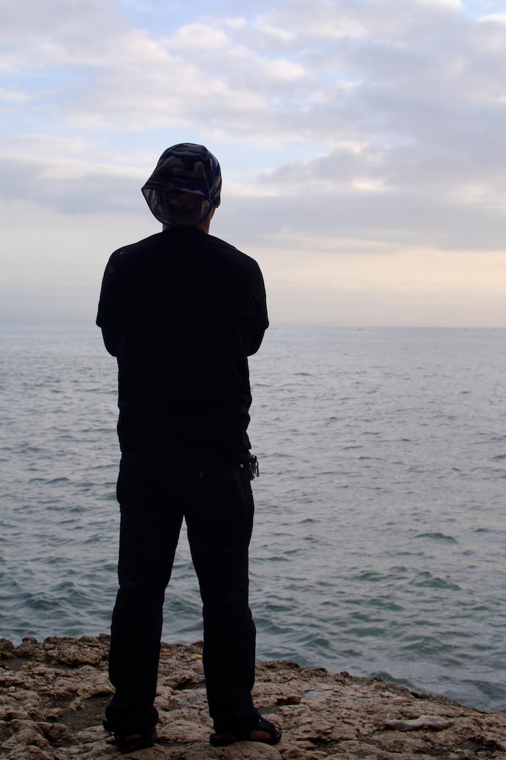 Foto uomo che guarda il mare contro il cielo