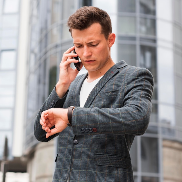 Uomo che guarda l'orologio e parla al telefono mentre va al lavoro