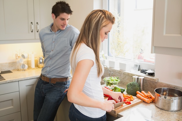 Uomo che guarda la donna che prepara le verdure