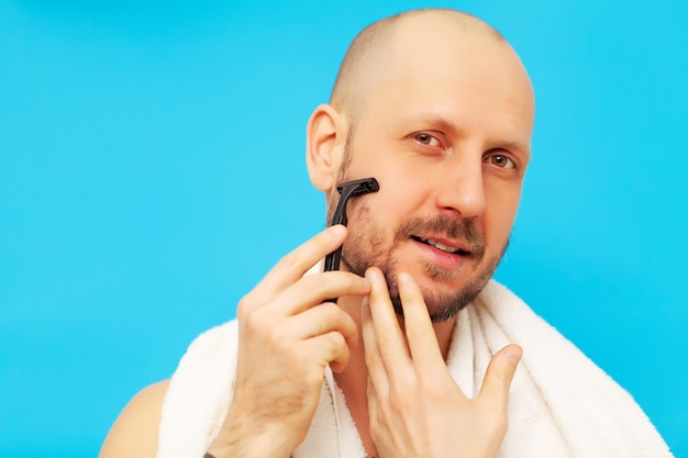 Uomo che guarda la telecamera e si rade il viso con il rasoio.