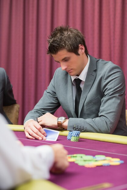 Uomo che guarda le sue carte nel gioco del poker