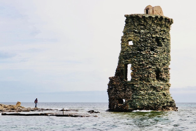 Uomo che guarda una torre abbandonata contro il cielo