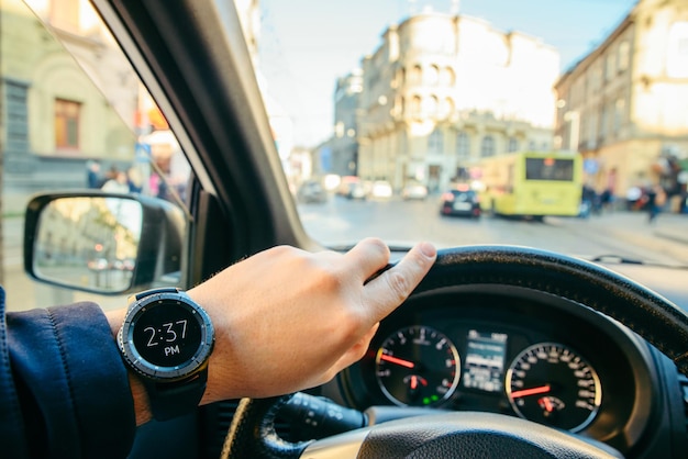 Uomo che guida l'auto nel traffico cittadino che guarda sull'orologio. visuale in prima persona. tardi per la riunione