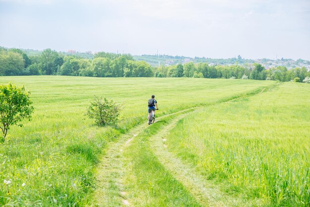 Uomo che guida la bicicletta da sentiero nello spazio verde della copia del campo dell'orzo