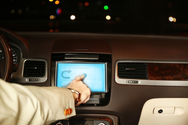 Uomo che guida la sua auto moderna di notte in primo piano della città