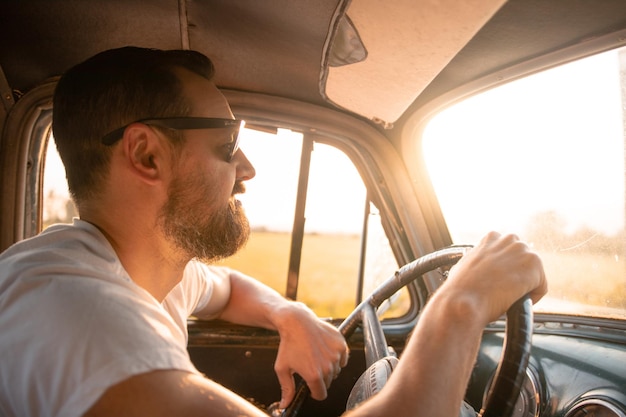 Uomo che guida un'auto al tramonto