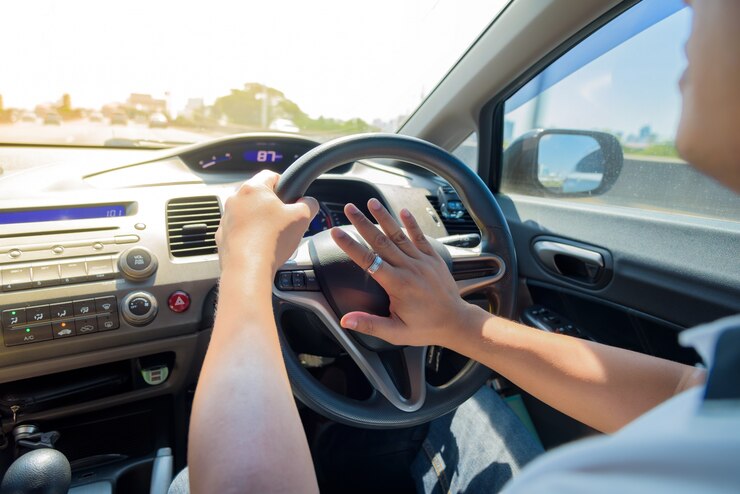 Uomo che guida un'auto con le mani che reggono il volante di un'auto e che suona il clacson.