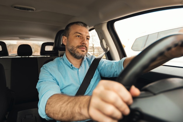 Uomo che guida un'auto nuova seduto all'interno di un'automobile in città