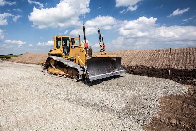 Uomo che guida un bulldozer sul cantiere contro il cielo