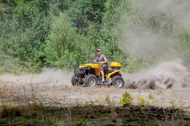 Uomo che guida un quad giallo ATV fuoristrada su una foresta sabbiosa