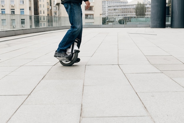 Uomo che guida veloce sul monociclo elettrico sulla strada della città.