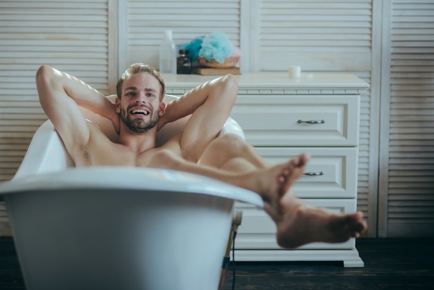 Uomo che ha mattinata gioiosa nella vasca da bagno gay sorridente nella vasca da bagno