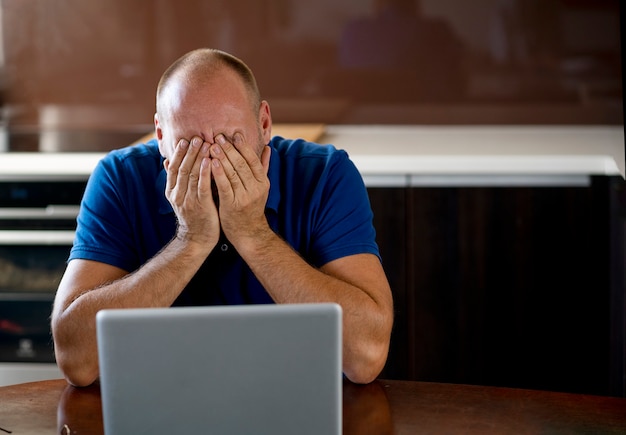 Uomo che ha tempo stressante lavorando sul computer portatile