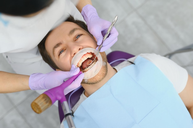 Uomo che ha una visita presso il dentista Bel paziente seduto sulla sedia presso l'ufficio del dentista nella clinica odontoiatrica