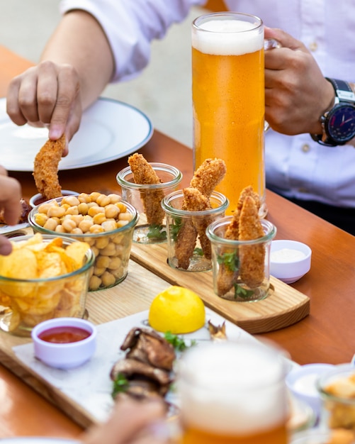 Uomo che immerge il pollo fritto al ketchup con la birra