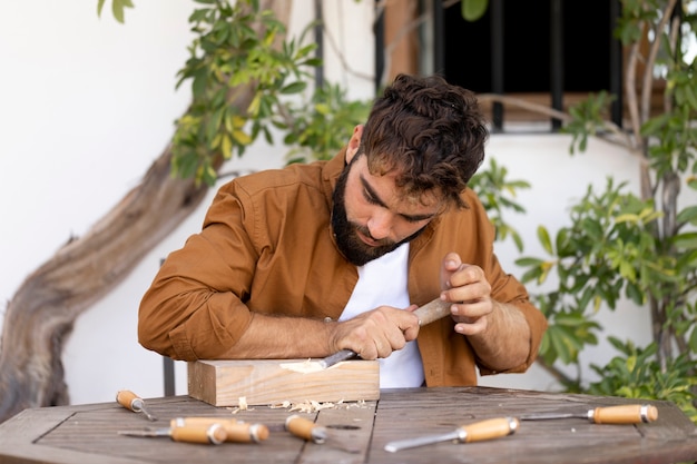 Uomo che incide su legno all'aperto