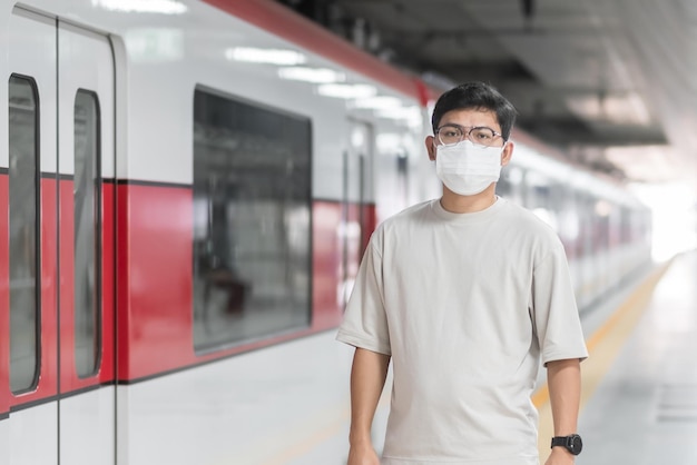 Uomo che indossa la maschera protettiva per prevenire l'inflessione del coronavirus durante l'attesa del treno. trasporto pubblico. distanziamento sociale, nuova normalità e sicurezza durante la pandemia di covid-19