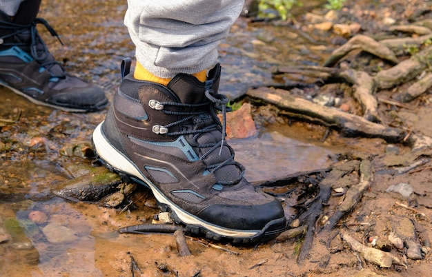 Uomo che indossa scarpe all'aperto e fa trekking in un parco fuori dal lago stivali nell'acqua del lago