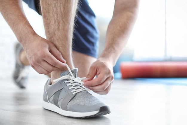 Uomo che indossa scarpe da ginnastica al chiuso primo piano