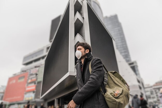 Uomo che indossa una maschera facciale a causa dell'inquinamento atmosferico e della protezione del virus Coronavirus