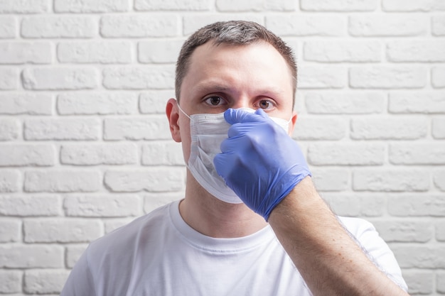 Uomo che indossa una maschera medica e guanti protettivi contro il muro