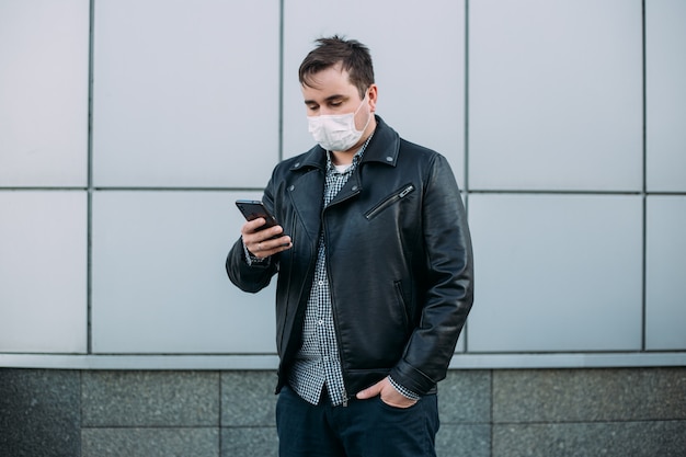 Uomo che indossa una maschera protettiva in strada utilizzando smartphone