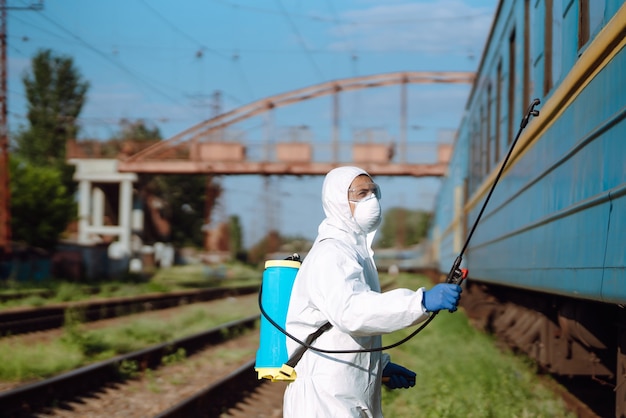 Uomo che indossa una tuta protettiva che disinfetta un treno pubblico.