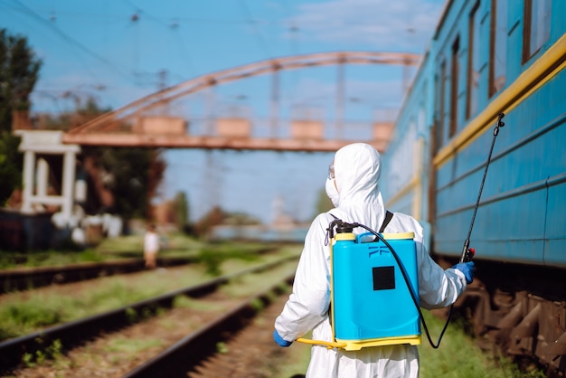 Uomo che indossa una tuta protettiva che disinfetta un treno pubblico.