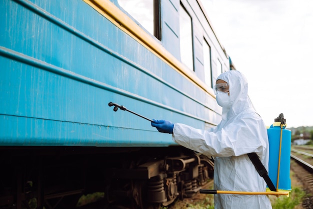 Uomo che indossa una tuta protettiva che disinfetta un treno pubblico.