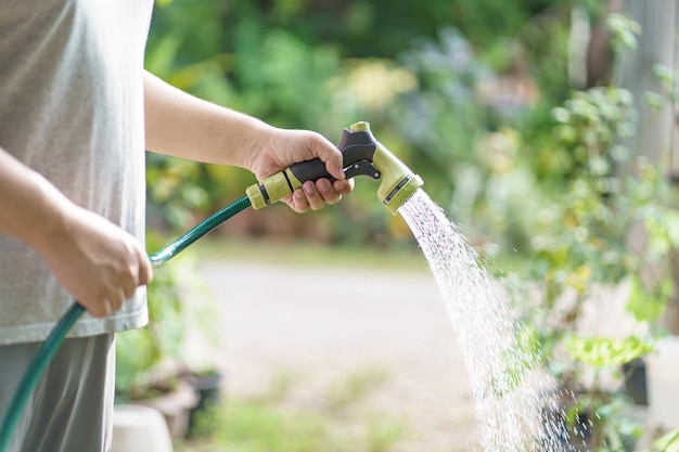 Uomo che innaffia le piante nel suo giardino Giardinaggio urbano che innaffia le verdure fresche natura e cura delle piante