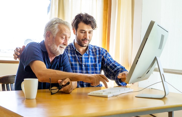 Uomo che insegna a un uomo anziano a usare il computer