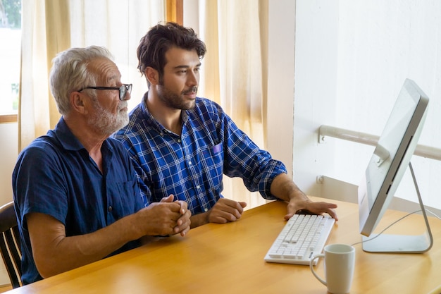 uomo che insegna all'uomo anziano all'utilizzo del computer