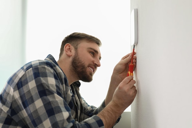 Uomo che installa il sistema di allarme di sicurezza sulla parete leggera a casa