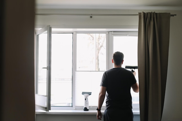 Uomo che lava e pulisce la finestra a casa Lavori domestici e pulizie domestiche