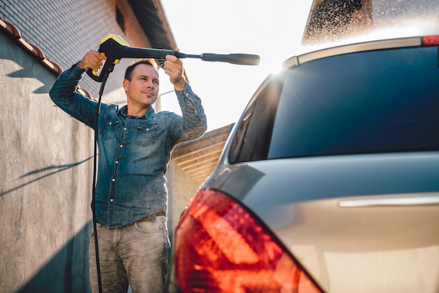 Uomo che lava la sua auto con idropulitrice