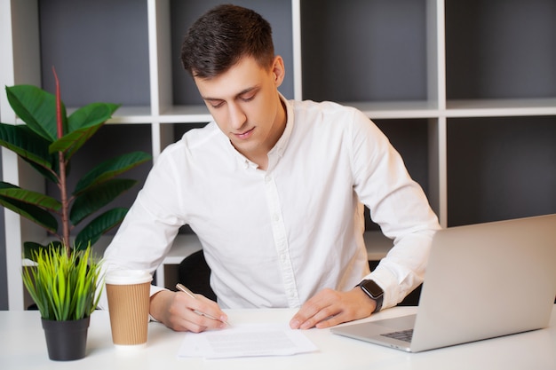 Uomo che lavora al computer in ufficio e compilando documenti