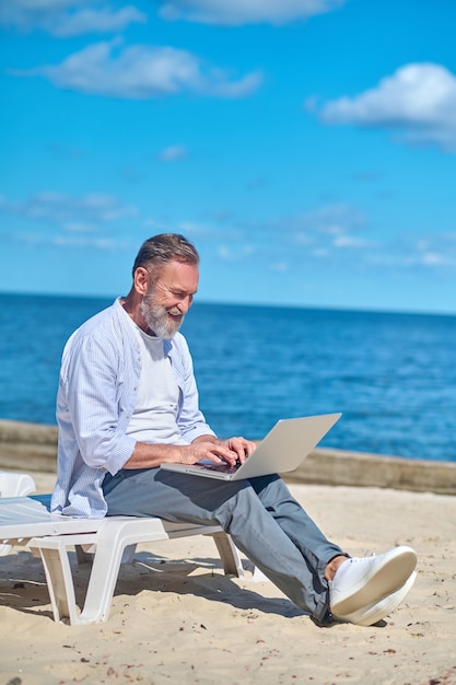 Uomo che lavora al computer portatile in riva al mare