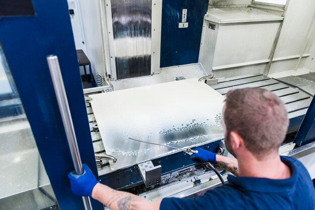 Uomo che lavora alla macchina in fabbrica industriale