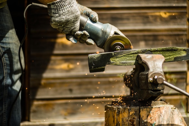 Uomo che lavora con la smerigliatrice vista ravvicinata sull'utensile Sega elettrica e mani del lavoratore con scintille Lavoratore che taglia il metallo con la smerigliatrice