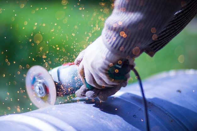 Uomo che lavora con la smerigliatrice vista ravvicinata sull'utensile Sega elettrica e mani del lavoratore con scintille Lavoratore che taglia il metallo con la smerigliatrice