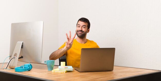 Uomo che lavora con laptot in un ufficio felice e contando tre con le dita