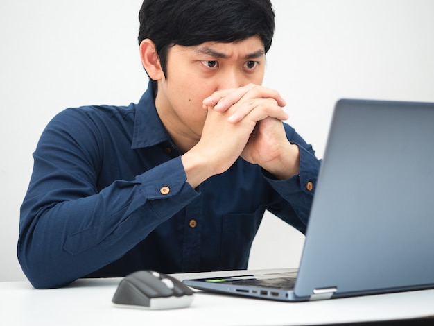 Uomo che lavora da casa e guarda il laptop sul tavolo sentendosi serio sul lavoro