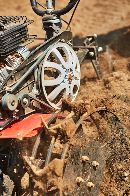 Uomo che lavora in giardino con Garden Tiller. Coltivatore del giardino per funzionare, alto vicino. Uomo con il trattore che coltiva campo alla molla. Agricoltura moderna, agricoltura tecnologica.