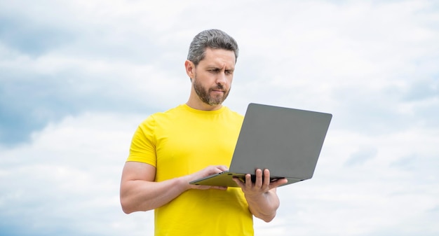 Uomo che lavora online sul computer sullo sfondo del cielo