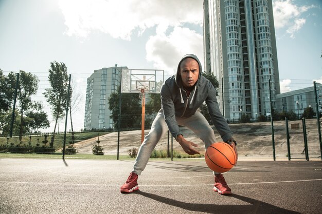 Uomo che lavora sodo. Un uomo simpatico e piacevole che viene al campo da basket mentre si allena per giocare bene a basket