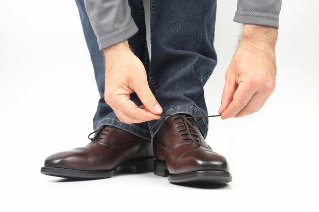 Uomo che lega i lacci delle scarpe su scarpe marroni classiche