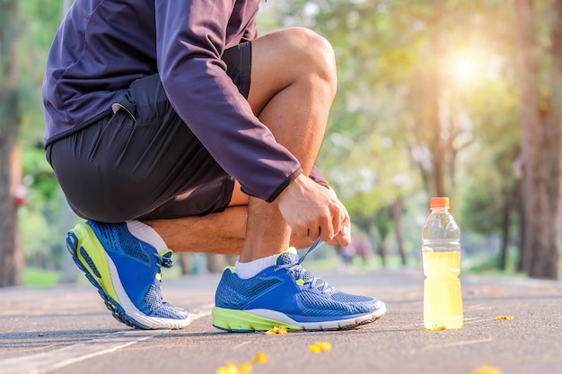 uomo che lega le scarpe da corsa nel parco